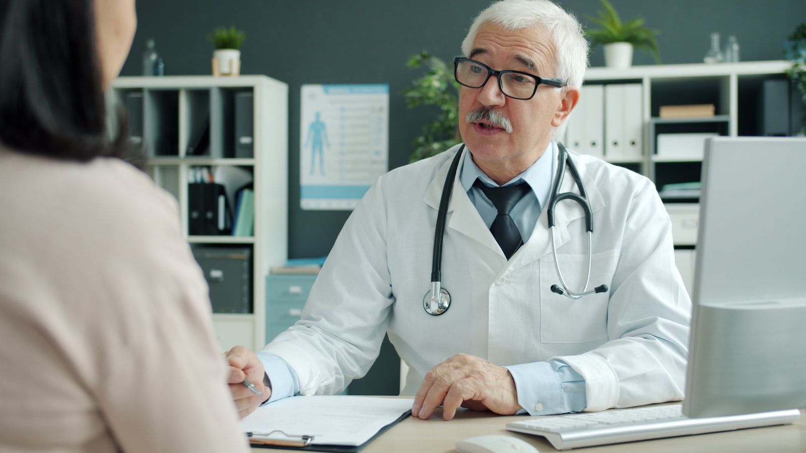 Doctor consulting warmly with a middle-aged patient in a bright consultation room