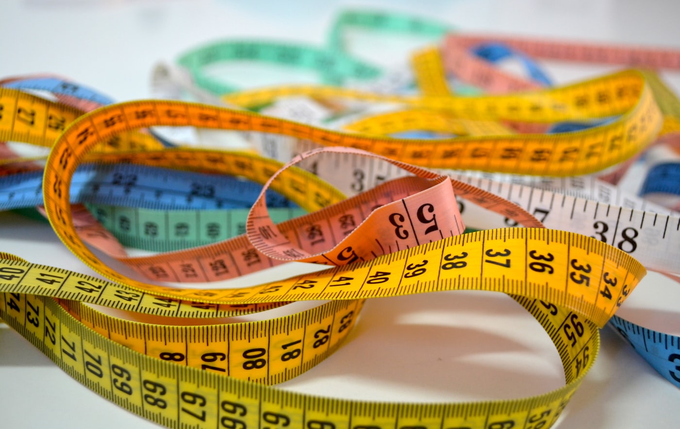 Doctor measuring a patient's waist circumference with a tape measure during a clinical assessment