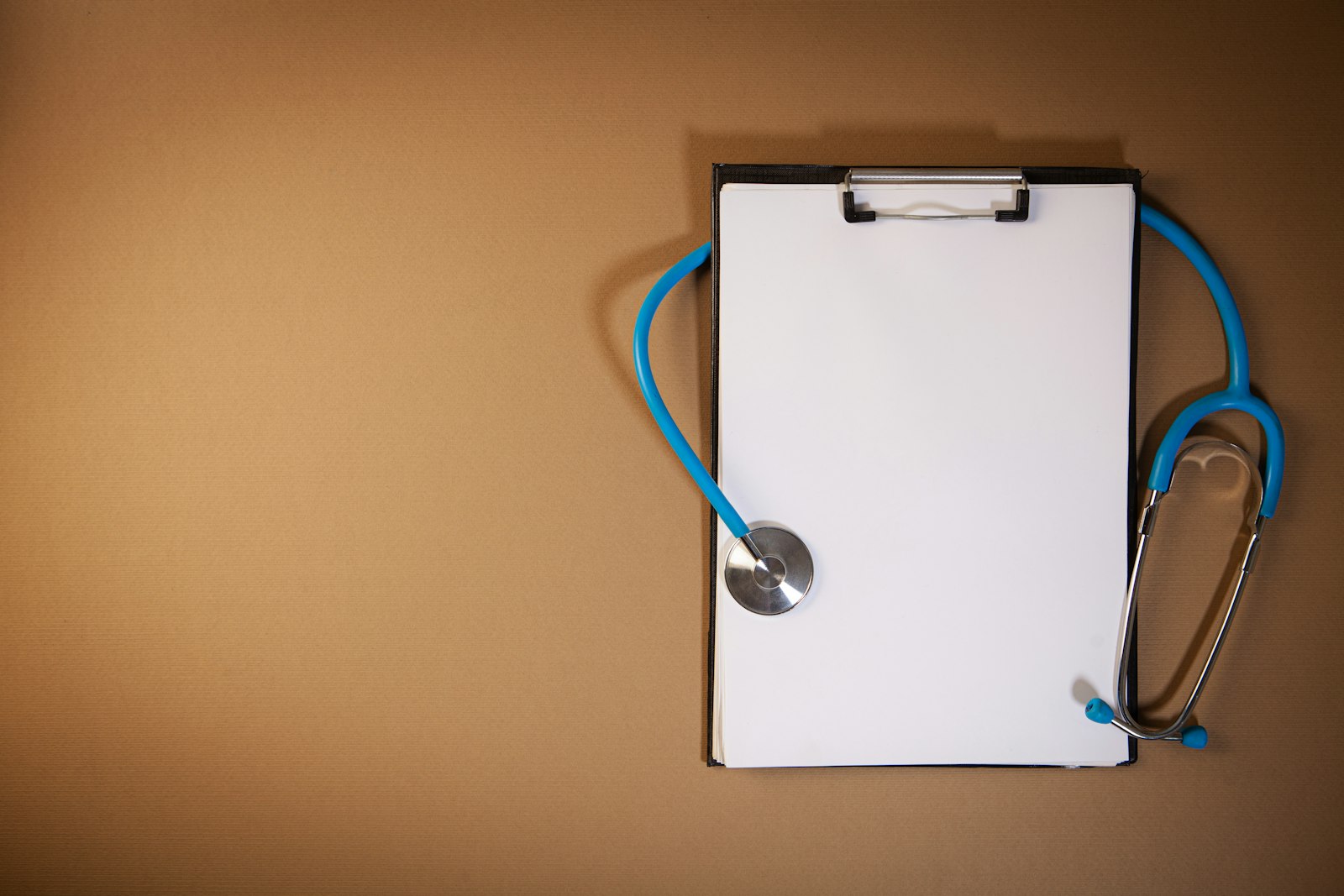 Stethoscope resting on a clipboard with a patient chart on a clinic desk